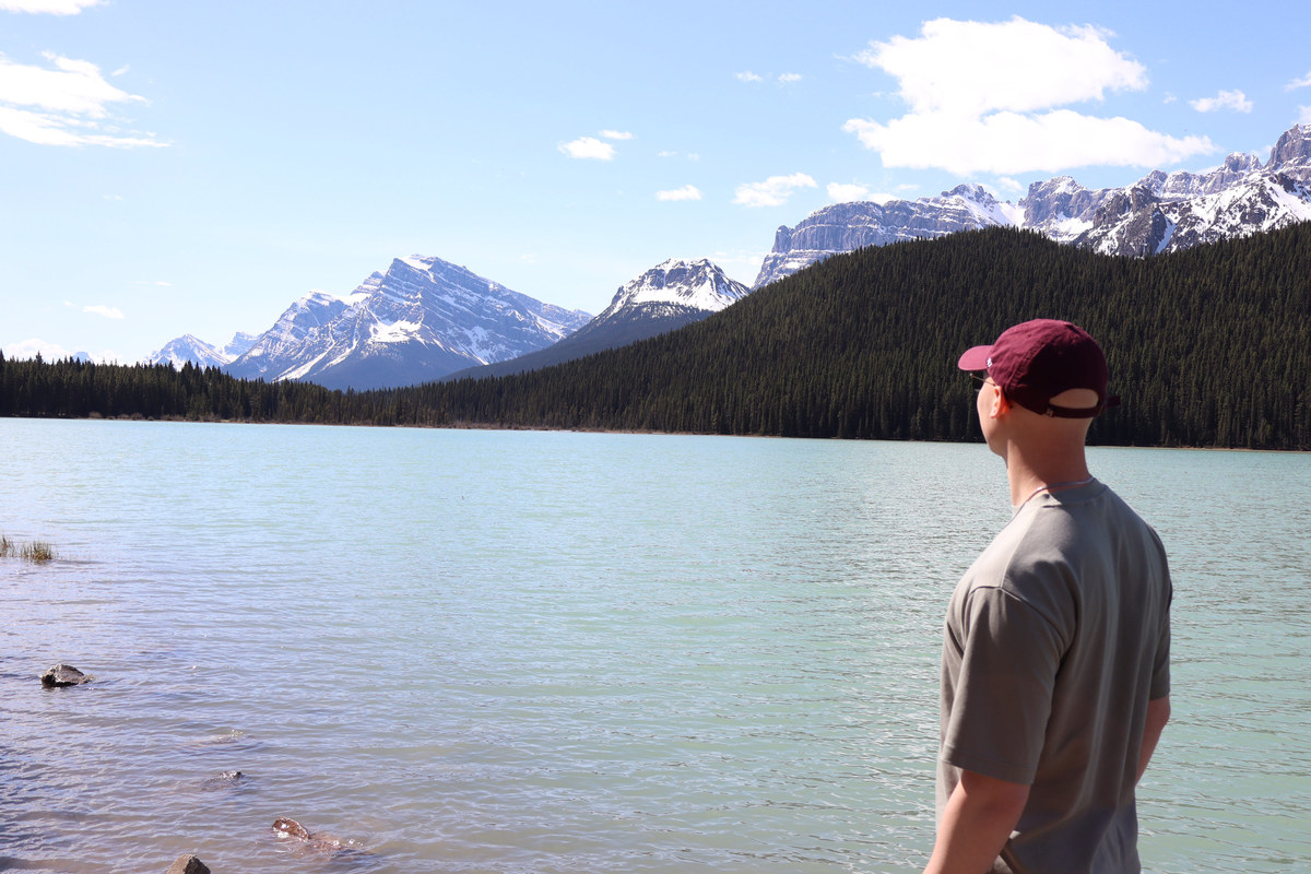 Alexander Ingare looking out across a glacial lake toward snow-capped peaks