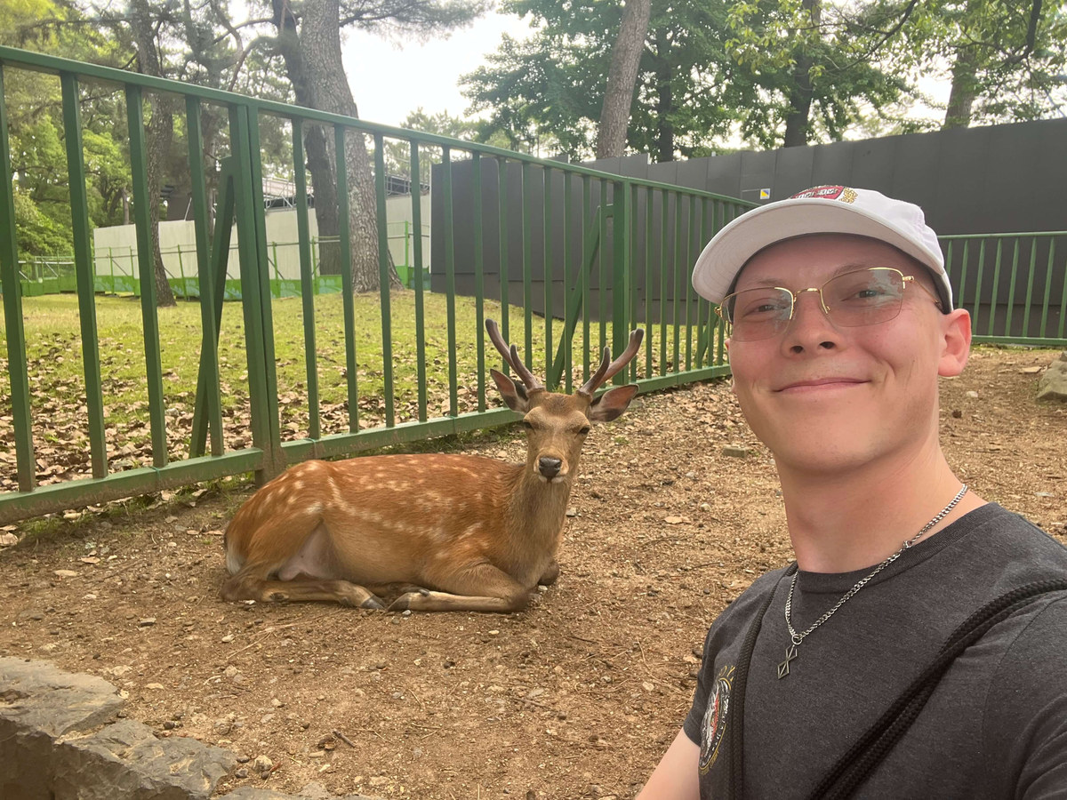 Alexander Ingare beside a sika deer resting in the shade of a park in Nara
