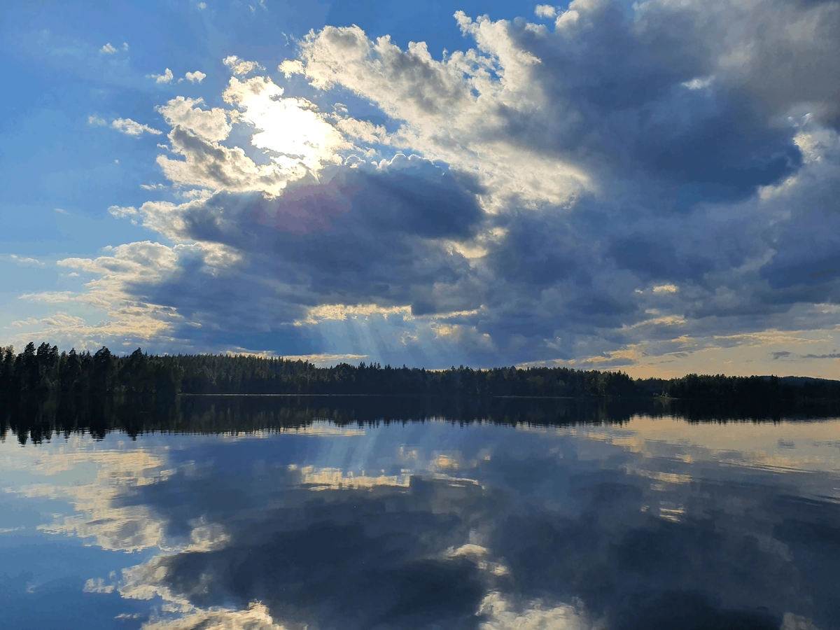 Cloud reflected in the mirror-still surface of a Swedish lake at dusk
