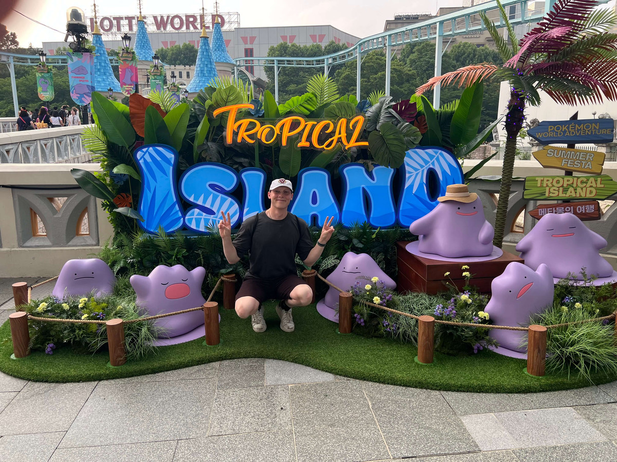 Alexander Ingare crouched in front of a Tropical Island sign at Lotte World