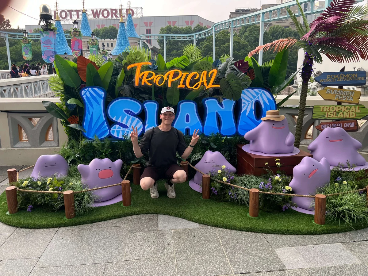 Alexander Ingare crouched in front of a Tropical Island sign at Lotte World
