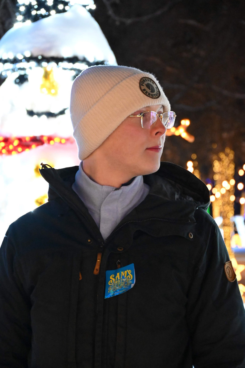 Alexander Ingare in a beanie and winter coat among strung lights at night