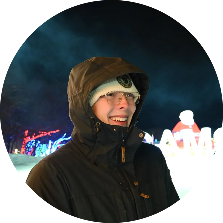Alexander Ingare in a hooded winter coat at night, standing on packed snow in front of an illuminated display